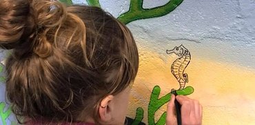 Close up of our artist painting the mural at The Bunker on Balmedie beach